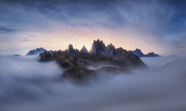 İtalya 'da gün batımında bulutlar arasında dolomitlerin zirvesi