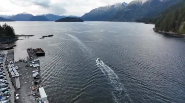 Horseshoe Körfezi 'nin, günbatımı gökyüzü, West Vancouver, British Columbia, Kanada' da yeşil dağların altında hizalanmış gemilerle çekilmiş insansız hava aracı görüntüsü.