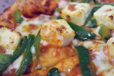 Pizza Paneer Makhani, kırmızı ve yeşil dolmalık biber, soğan, paneer ve mozzarella peyniri ve ince hamur hamuruyla yapılan ev yapımı lezzetli pizza.