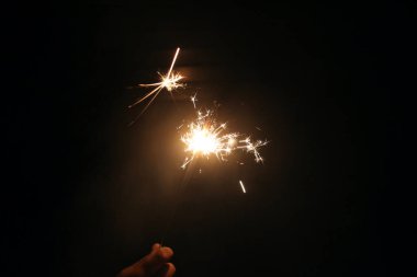 Siyah arka planda maytap tutan bir el.