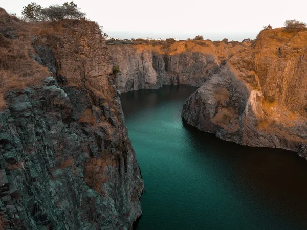 A drone footage of a canyons and teal turbid waters the glare of a cloud on water