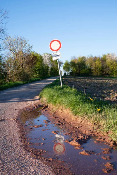Path in the countryside, warning sign for cars, no enty, puddle after the rain, landscape in Germany