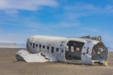 Mavi bir gökyüzünün altında, kumların üzerinde eski bir uçağın yakın çekimi.