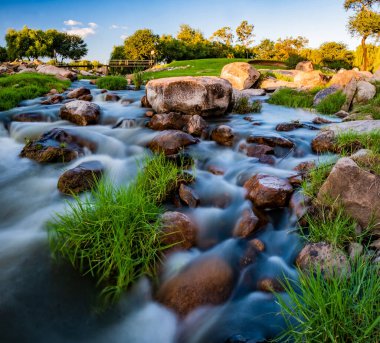 Kırsalda, güneşin altında kayaların arasından akan bir nehrin dikey yakın çekimi.