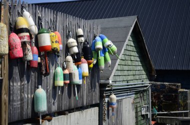 Sahildeki bir duvarda birçok şamandıra asılı.