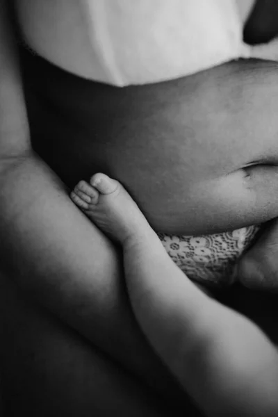 用灰度的母亲的腹部垂直拍摄的新生儿的脚 — 图库照片