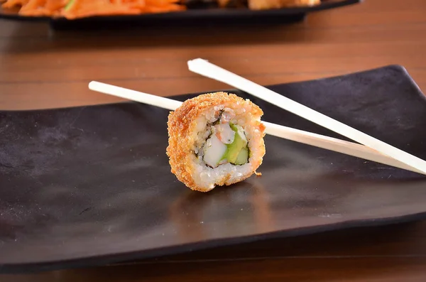 Ein Stück Gebratene Sushi Rolle Auf Dunklem Steinteller Mit Essstäbchen — Stockfoto