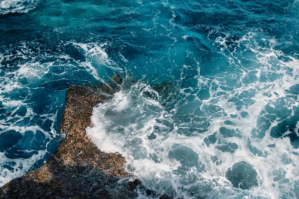 海の波が水の中の岩の層に飛び散る — ストック写真