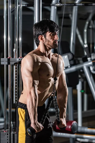 Spor salonunda spor yapan kaslı beyaz bir adamın dikey çekimi.