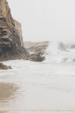 Yağmurlu bir günde kayalara çarpan dalgaların dikey çekimi. Punta Corveira, Lugo, Galiçya, İspanya.