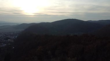 Bulutlu bir gökyüzüne karşı ağaçlarla kaplı büyük kayalık bir dağ.