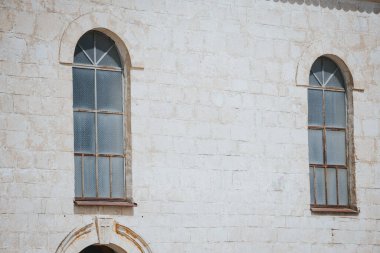 Güneş ışığı altındaki bir binanın iki eski kemerli penceresinin yakın çekimi