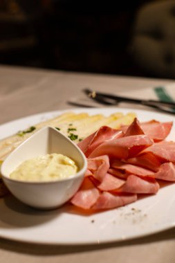 Beyaz tabakta beyaz kuşkonmaz, jambon ve Bolzano sosu.