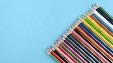 Mavi arka planda bir demet renkli kalem. Kalem rengi üzerine seçici odak  