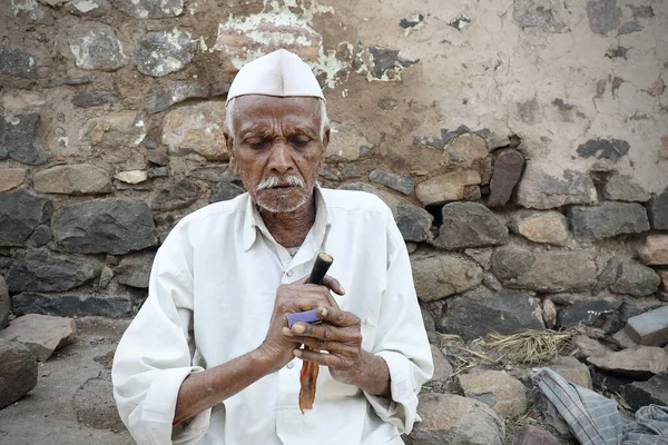 村の服を着ているインドの貧しい村の老人の選択的な焦点チラム 彼の家の外のベディやビディやタバコと呼ばれる — ストック写真