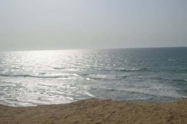 Deniz üzerindeki bulutlu gökyüzü yazın kumlu sahilden yakalanır.