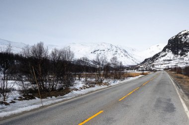 Karlı dağların arka planına karşı boş yol. Hemsedal, Norveç, Riksvei 52.