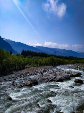 Güneşin doğuşuyla dağ katmanlı kayalık bir dere manzarası.