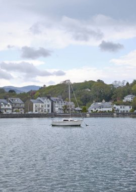 Snowdonia, Galler 'deki özel evlere karşı denizde yüzen bir teknenin dikey görüntüsü.