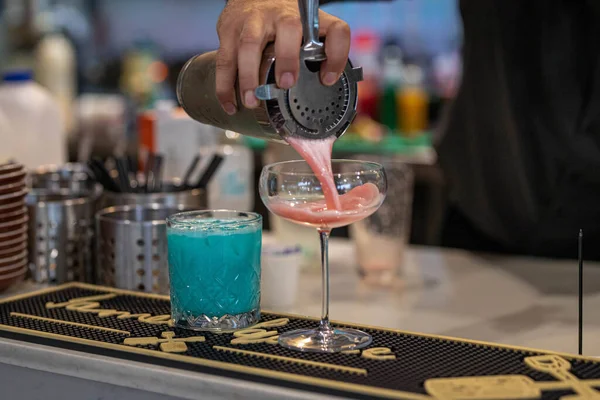 A man's hand pouring a drink in a glass cup in a bar