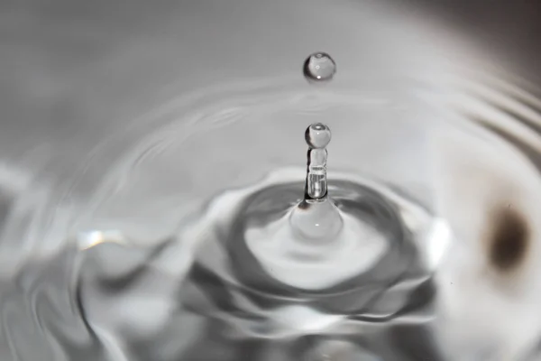 Een Grijsschaal Close Van Een Druppel Water Die Een Wateroppervlak — Stockfoto