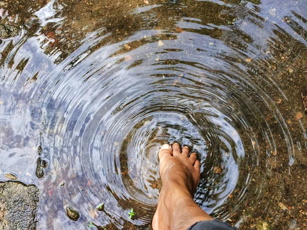 A foot on a water puddle creating a circles pattern