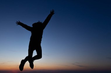 Zıplayan bir adamın güzel bir günbatımı geçmişine yakın çekim silueti, özgürlük kavramı.