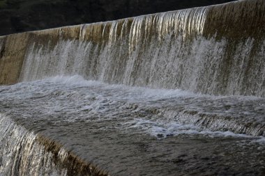 Güzel bir şelale ve ağaçların arasındaki parktaki beton yol.