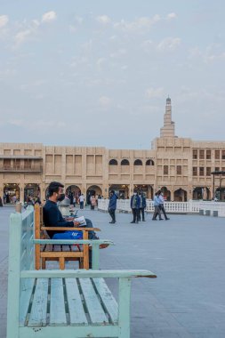 Souq Waqif Doha, Katar 'da çizim yaparken bankta oturan bir adamın dikey çekimi.