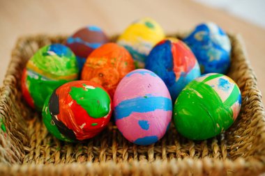 Ahşap bir masanın üzerinde saman sepetinde boyalı bir paskalya yumurtasının yakın plan fotoğrafı.