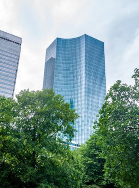 Frankfurt, Almanya 'da gökdelenin güzel bir görüntüsü. Mavi gökyüzüne karşı yeşil ağaçların arkasında.