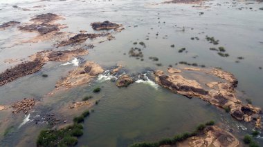 Nehir kıyısında bir günbatımı. Nehirdeki şelalenin pürüzsüz suları orman manzarasında