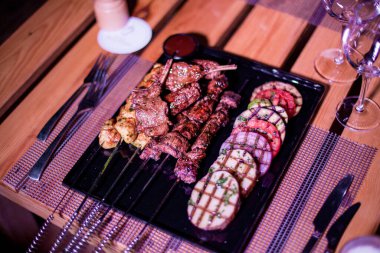 Izgara domates, patates ve soğanlı bir tabak tavuk ve biftek.