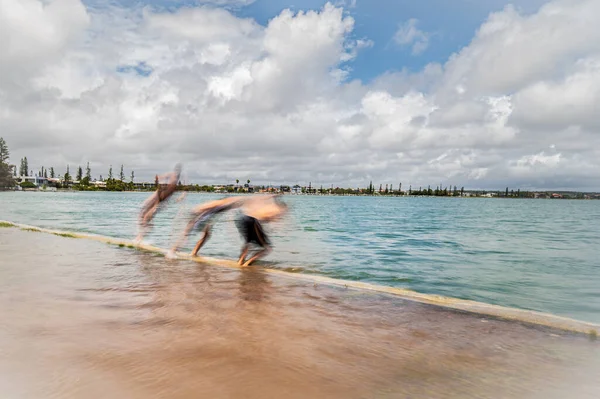 余分な満潮の間に海岸の水に飛び込む人々の長い露出ショット 気候変動 — ストック写真