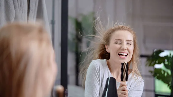 ウクライナの幸せな白人の若い女性がヘアドライヤーで彼女の髪を吹いて ブラシで歌います — ストック写真