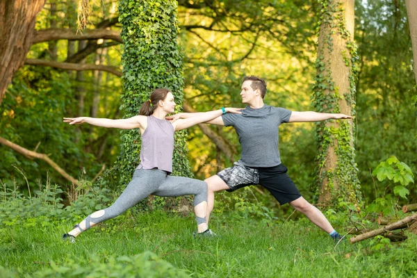一个年轻的白人女人和一个在大自然中做瑜伽的男人 — 图库照片