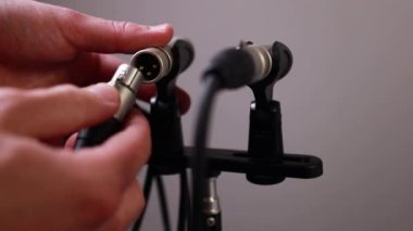 Bir kabloyu yoğunlaştırıcı mikrofonlara bağlayan ellerin yakın çekimi