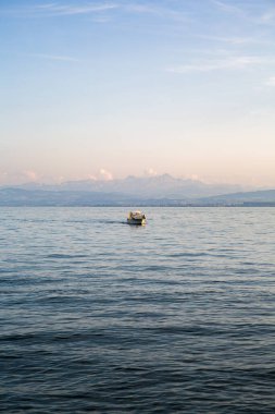 Günbatımında Constance Gölü 'nde bir teknenin dikey çekimi.