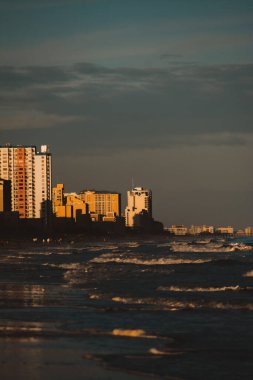 Alacakaranlıkta kıyıları yıkayan dalgaların dikey görüntüsü.