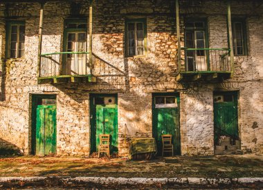 Balkonları ve Divri köyünde yeşil ahşap kapıları olan eski bir taş bina.