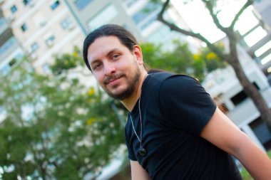 Yakışıklı beyaz bir erkek güneşli bir günde parkta eğleniyor.