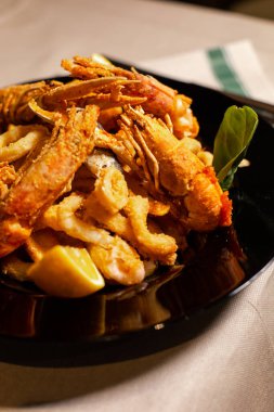 Siyah tabakta servis edilen lezzetli karides ve mürekkep balıkları.