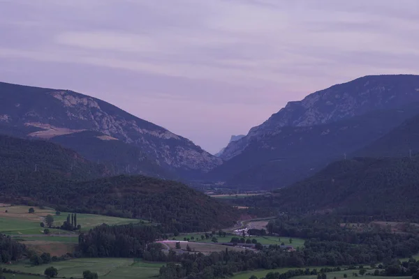 A Beautiful scene of a dry green land and mountains under a cloudy blue sky