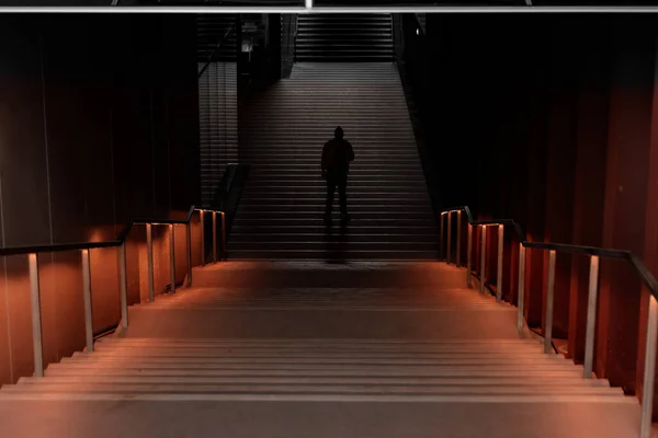 階段の間の地下トンネルの真ん中に一人で立っている男のシルエット — ストック写真