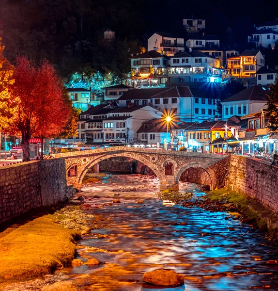 Prizren şehir merkezinde taş köprüsü olan ve geceleri binalar ve ağaçlarla kaplı bir nehir, Priştine Kosova