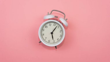 Pembe arka plandaki beyaz alarmlı saate odaklan. Düşmüş bir beyaz alarm saati zamanın nasıl boşa harcanamayacağını gösteriyor..