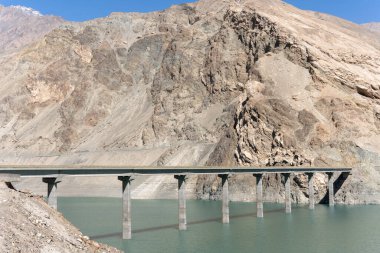 Kayalık dağlarla çevrili bir gölün üzerindeki güzel bir köprü manzarası.