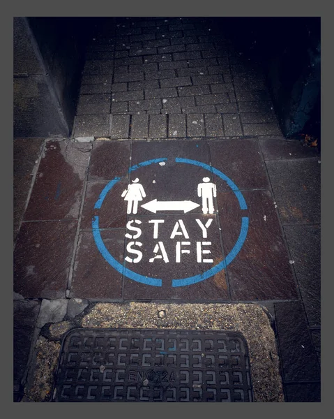 Vertikální Záběr Pouliční Cedule Zemi Nápisem Stay Safe Pro Lidi — Stock fotografie