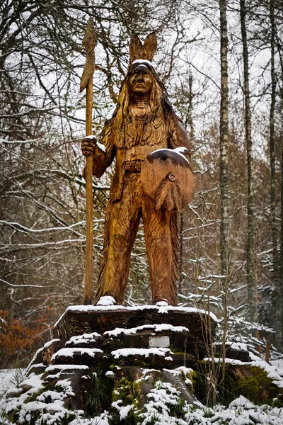降雪後の森林の台座の上にインディアンの木製の図の等身大 — ストック写真