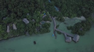 Yeşil bitki örtüsüyle çevrili evleri olan bir tatil köyünün kuş bakışı görüntüsü..